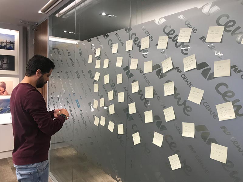 My colleague sorting postits on a glass office wall